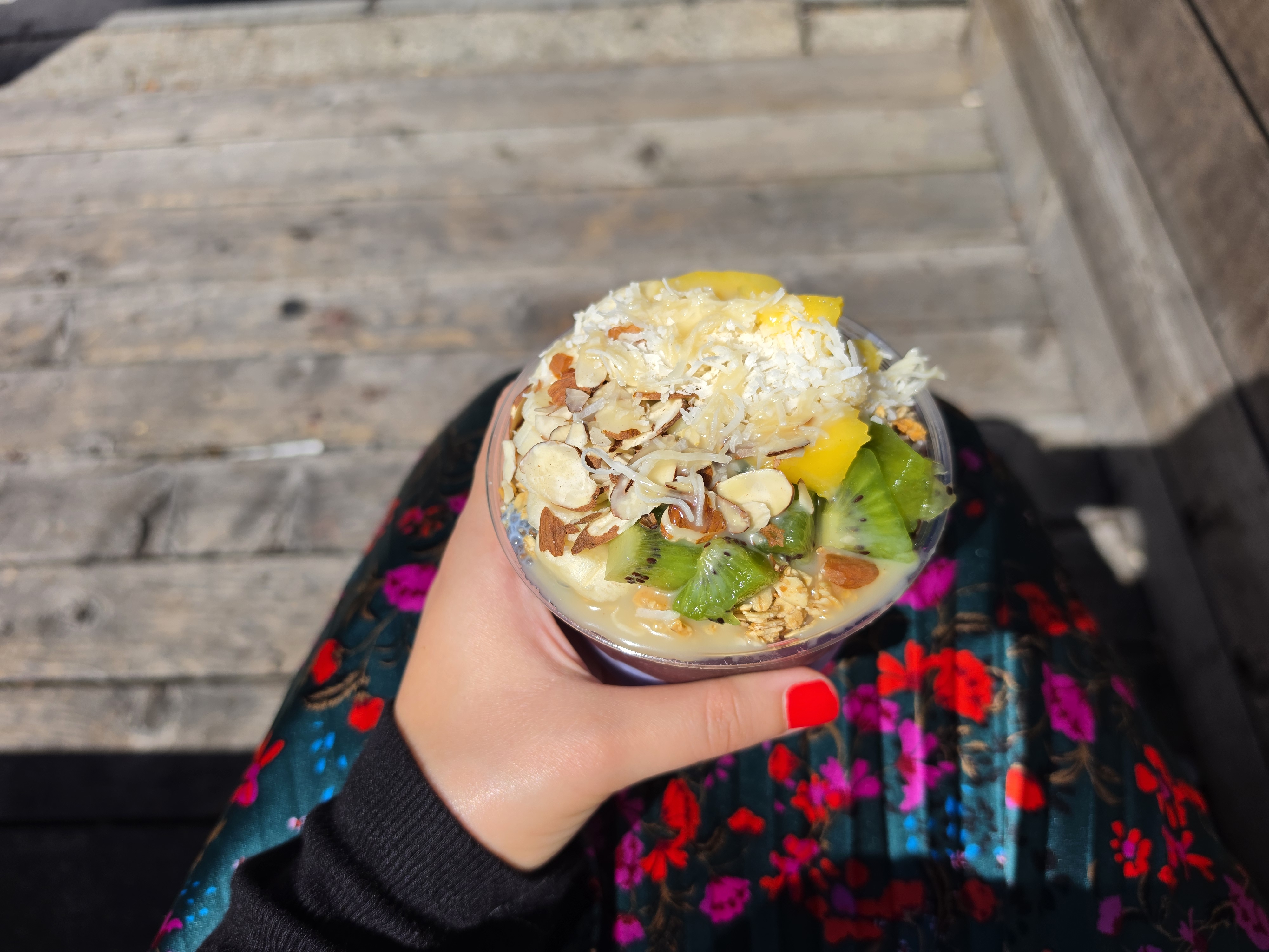 An acai bowl with fruit on top, in someone's hand