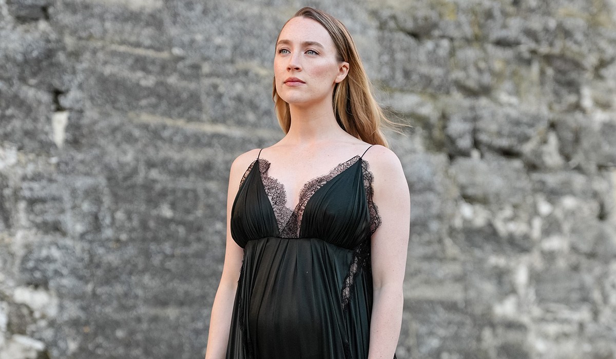 AVIGNON, FRANCE - MAY 22: Saoirse Ronan wears a black pleated low-neck dress with dark green hue featuring delicate lace trim and thin straps. Hair is styled straight and parted in the center. Black sandals complete the look, outside Louis Vuitton, during the Louis Vuitton Cruise 2026 at Palais Des Papes, on May 22, 2025 in Avignon, France. (Photo by Edward Berthelot/Getty Images)