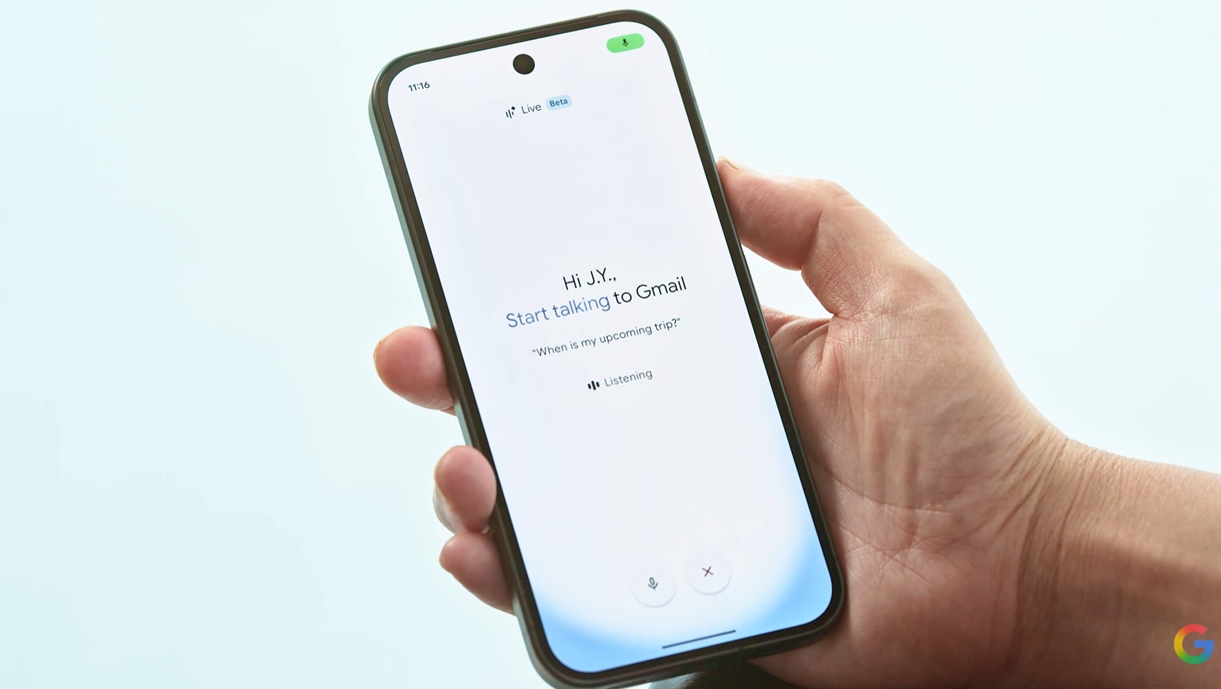 A hand holds a smartphone against a light background. On screen is Google's beta AI Voice feature for email with text that says, "Hi J.Y., Start talking to Gmail. "When is my upcoming trip?" Listening