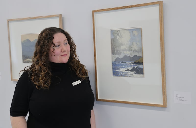 Anastasia M, who works at the Limerick City Gallery of Art, with the Paul  Henry painting Achill Head (1918-20) from the LCGA permanent collection. Photograph: Bryan O’Brien/The Irish Times 