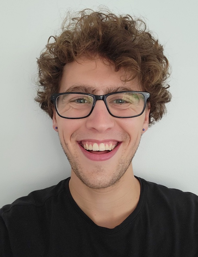 Man with wide smile, eyeglasses and very curly hair.