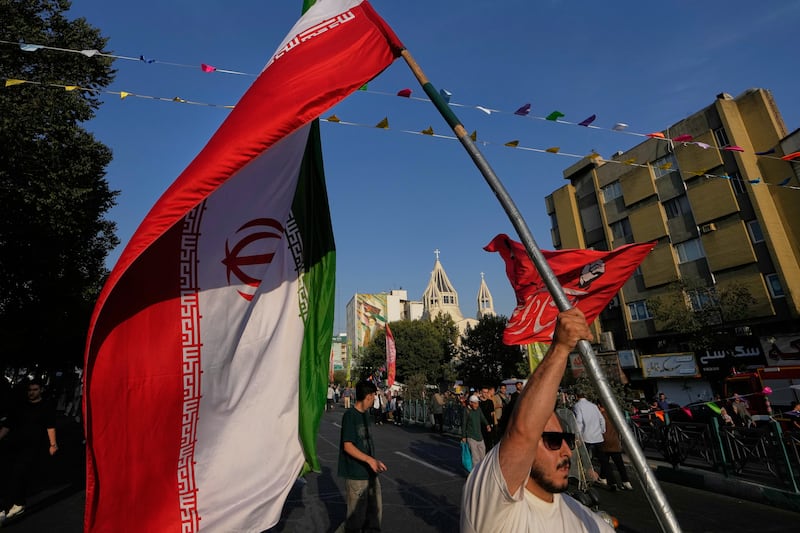 A man holds an Iranian flag during a street celebration marking the Prophet Muhammad’s birthday in Tehran (Vahid Salemi/AP)