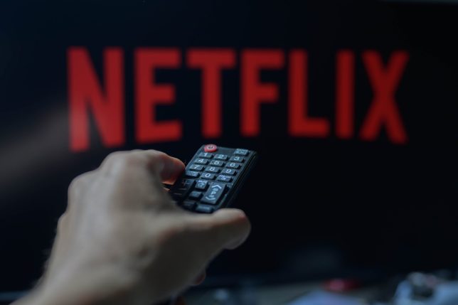 A person is holding a TV remote with Netflix visible in the background in this photo illustration taken in Brussels, Belgium, on May 5, 2024. (Photo by Jonathan Raa/NurPhoto via Getty Images)