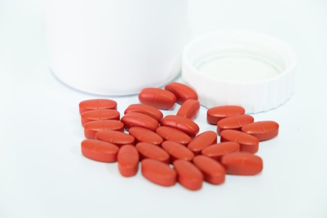 Red, Yellow,Pink tablets and white medicine bottles placed on a white background, Medical concept