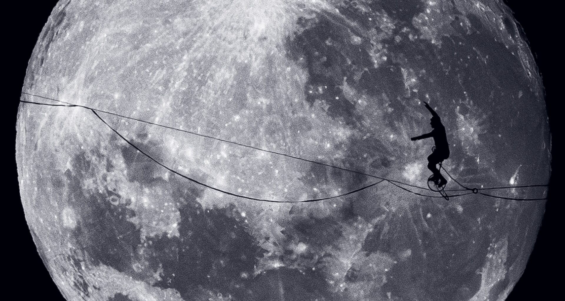 A person rides a unicycle along a tightrope with the moon behind them.