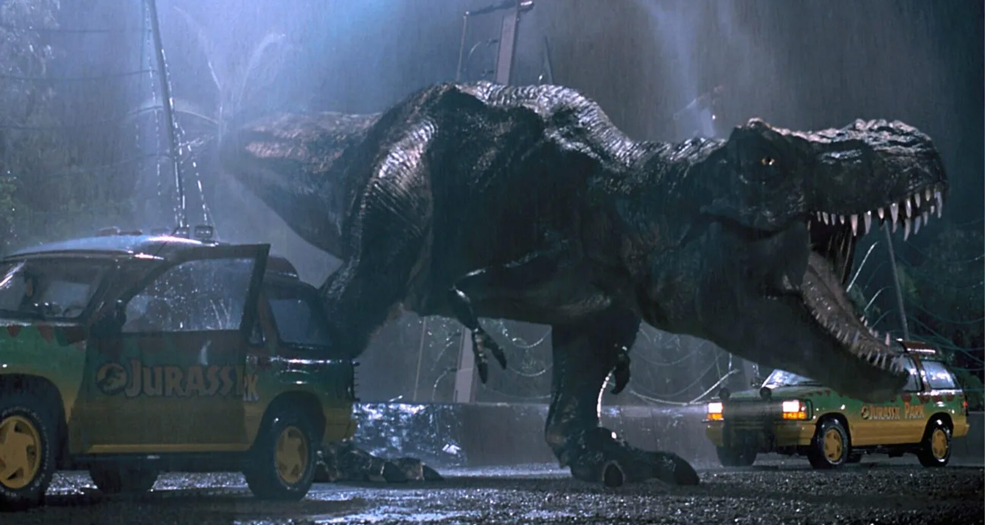 A T. rex from Jurassic Park roaring near two SUVs.