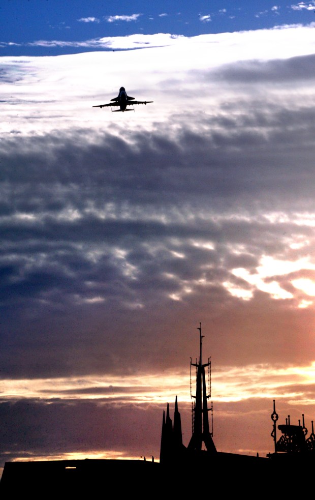 The NASA 747 ferrying the Space Shuttle Endeavour gains altitude as it is seen passing over the spires of Space Mountain at sunrise, in the Magic Kingdom at Walt Disney World, in Lake Buena Vista, on Wednesday, September 19, 2012. (Joe Burbank/Orlando Sentinel File)