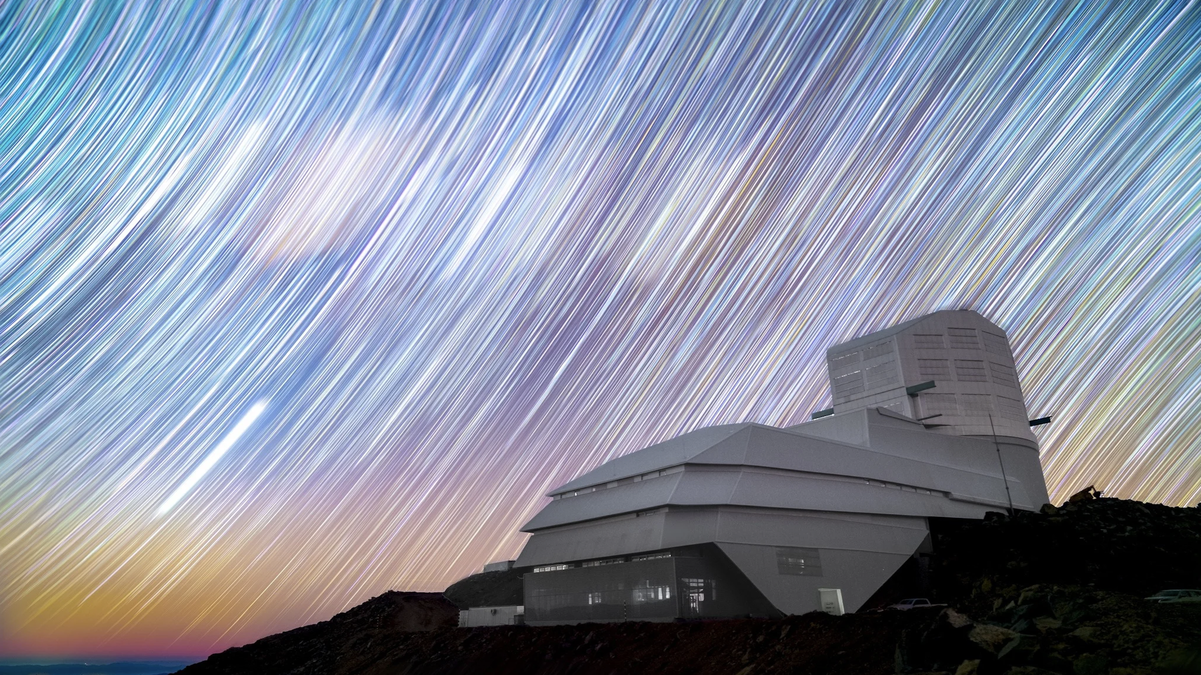 A long-exposure photo of the Vera C. Rubin Observatory in front of a starry sky.