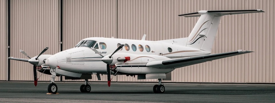 A two-engine aircraft sitting in front of a hangar.