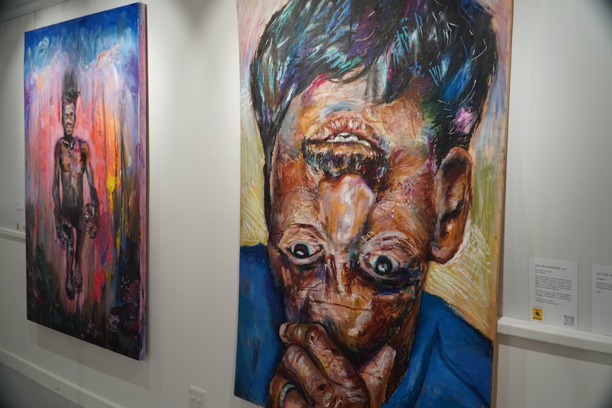 Two colourful paintings hang on the wall.