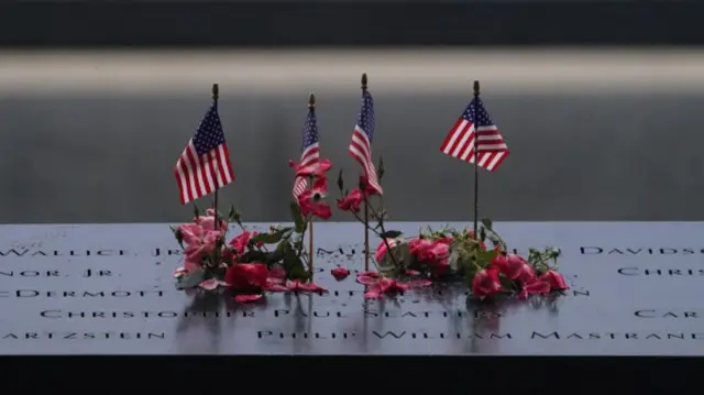 Flags and flowers adourn the names of victims of the 9/11 attacks at one of the memorial pools in New York City