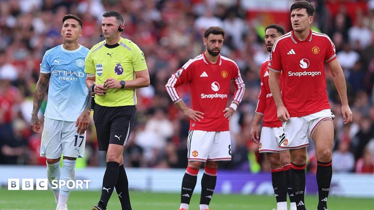 Players of Manchester City and Manchester United stand around as a VAR review is carried out