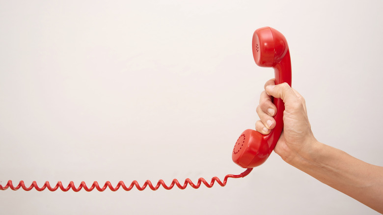 An old school telephone being held in a hand