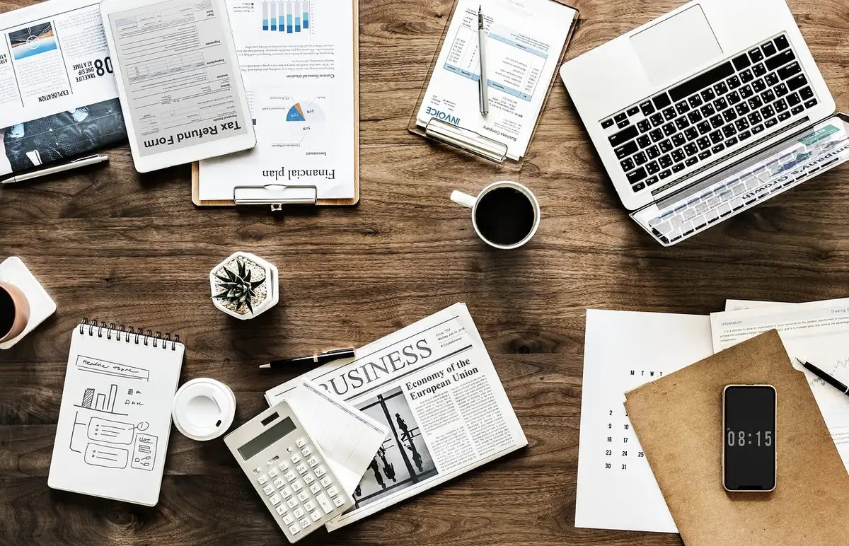 Office workers at desks with computer screens, some gathering documents, a sense of workplace activity slowing down
