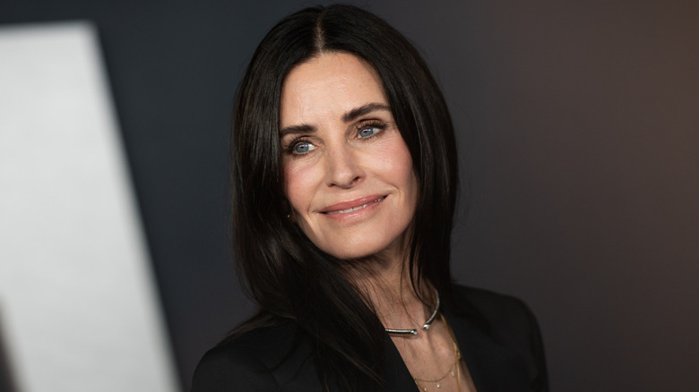 Courteney Cox wearing black in front of a black and white background