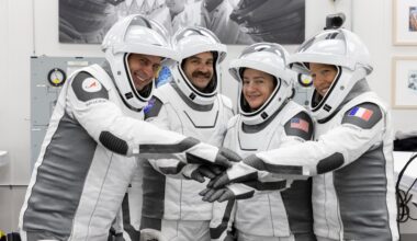 NASA’s SpaceX Crew-12 members stand side by side in their spacesuits with the face guard up. Each astronaut has their arm outstretched in front of them to pile their hands on top of one another as they smile and pose for a team photo. The astronauts are at the Neil A. Armstrong Operations and Checkout Building at the agency’s Kennedy Space Center in Florida ahead of launch to the International Space Station on Feb. 13, 2026, from left, Roscosmos cosmonaut Andrey Fedyaev, NASA astronauts Jack Hathaway and Jessica Meir, and ESA (European Space Agency) astronaut Sophie Adenot.