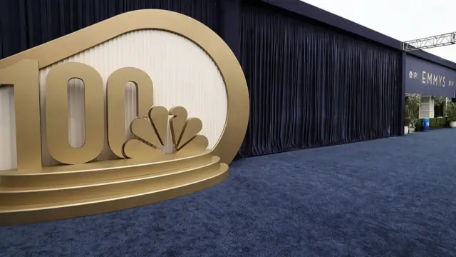 Blue carpet and a large gold sign showing the NBC logo