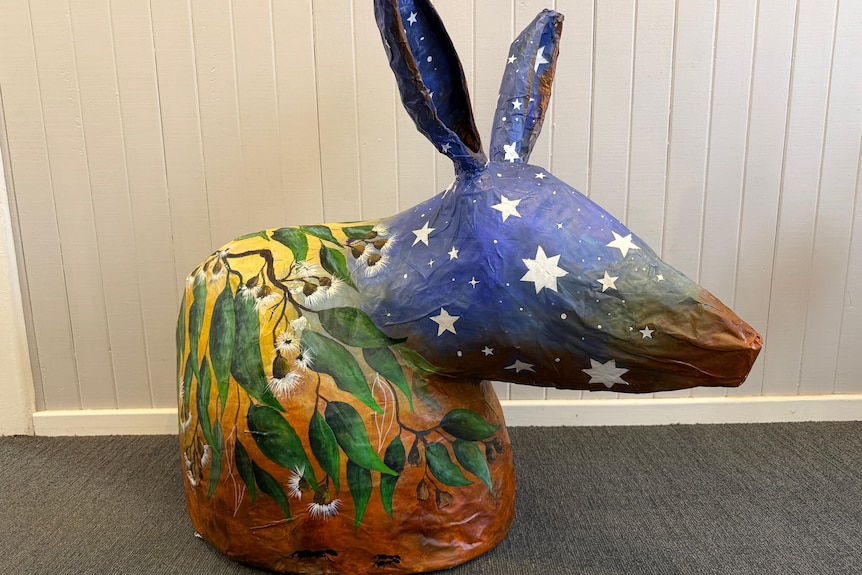 a large paper mache bilby with a star, gum leaf and red dirt design
