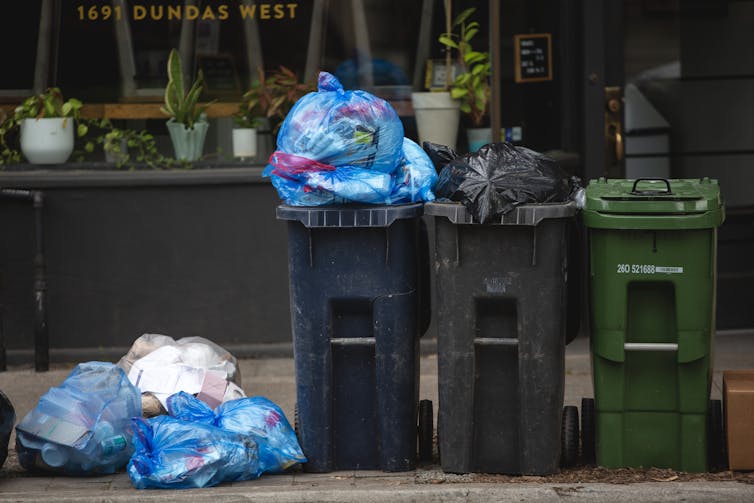 Recycling bins and other refuse are seen at the side of the street