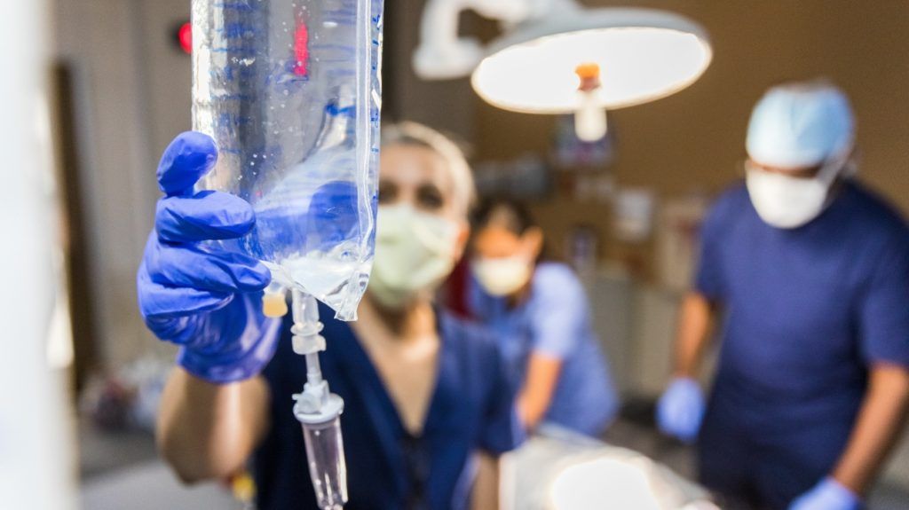 A medical professional is checking an IV bag.