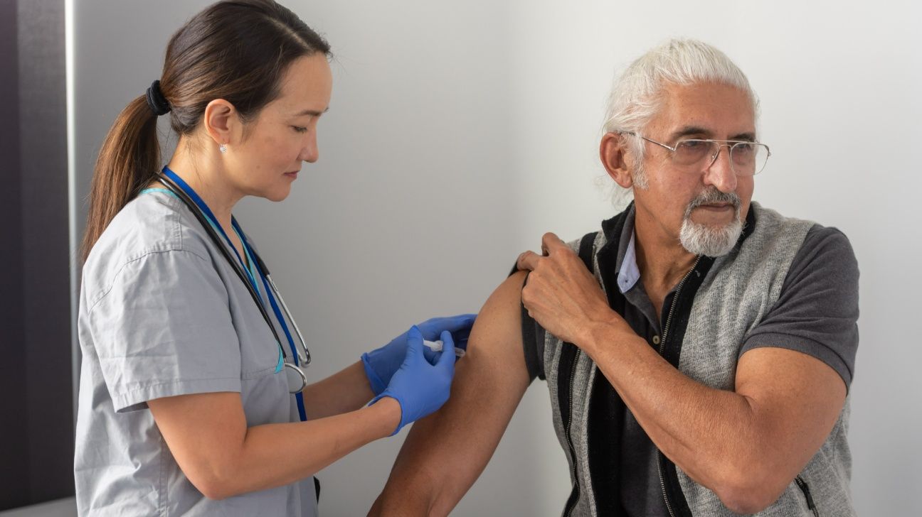 Older adult male receiving a shot from a nurse