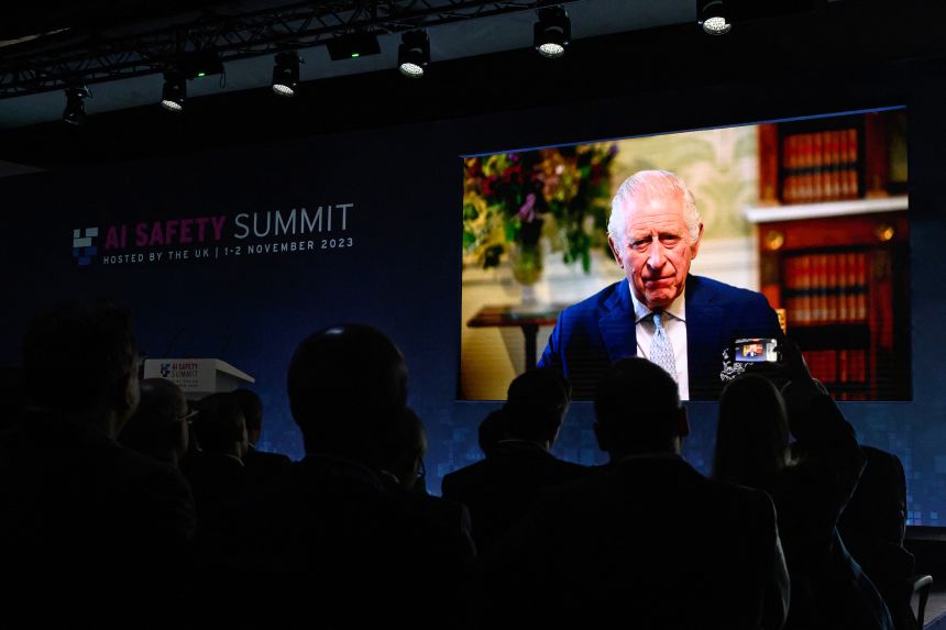 A screen displays a pre-recorded video message from Britain's King Charles III during the UK Artificial Intelligence (AI) Safety Summit at Bletchley Park, England, on November 1, 2023.
