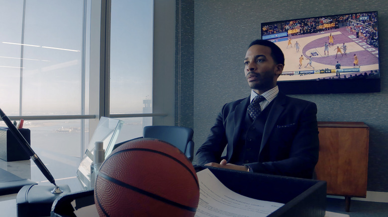 Ray Burke sitting at a desk, frowning, in 