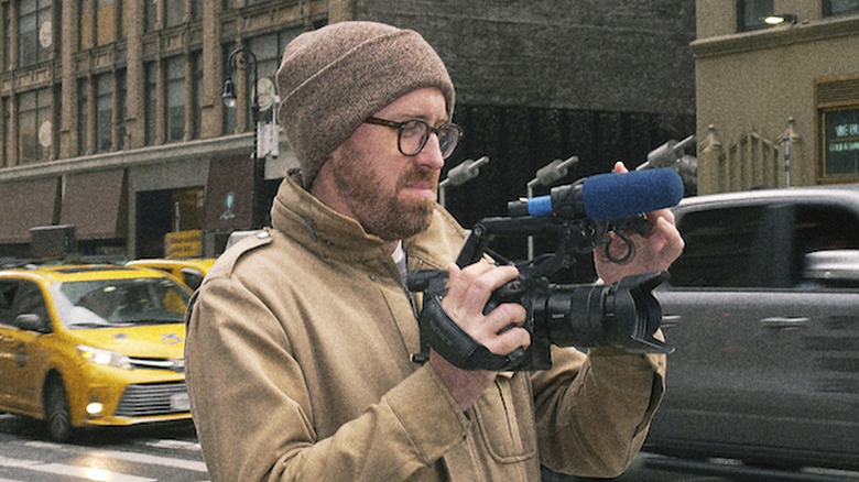 John Wilson holding camera on busy street