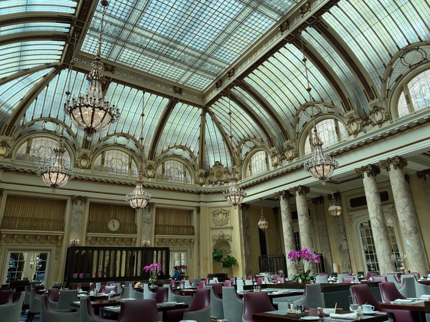A hotel lobby with a glass ceiling and chandeliers 