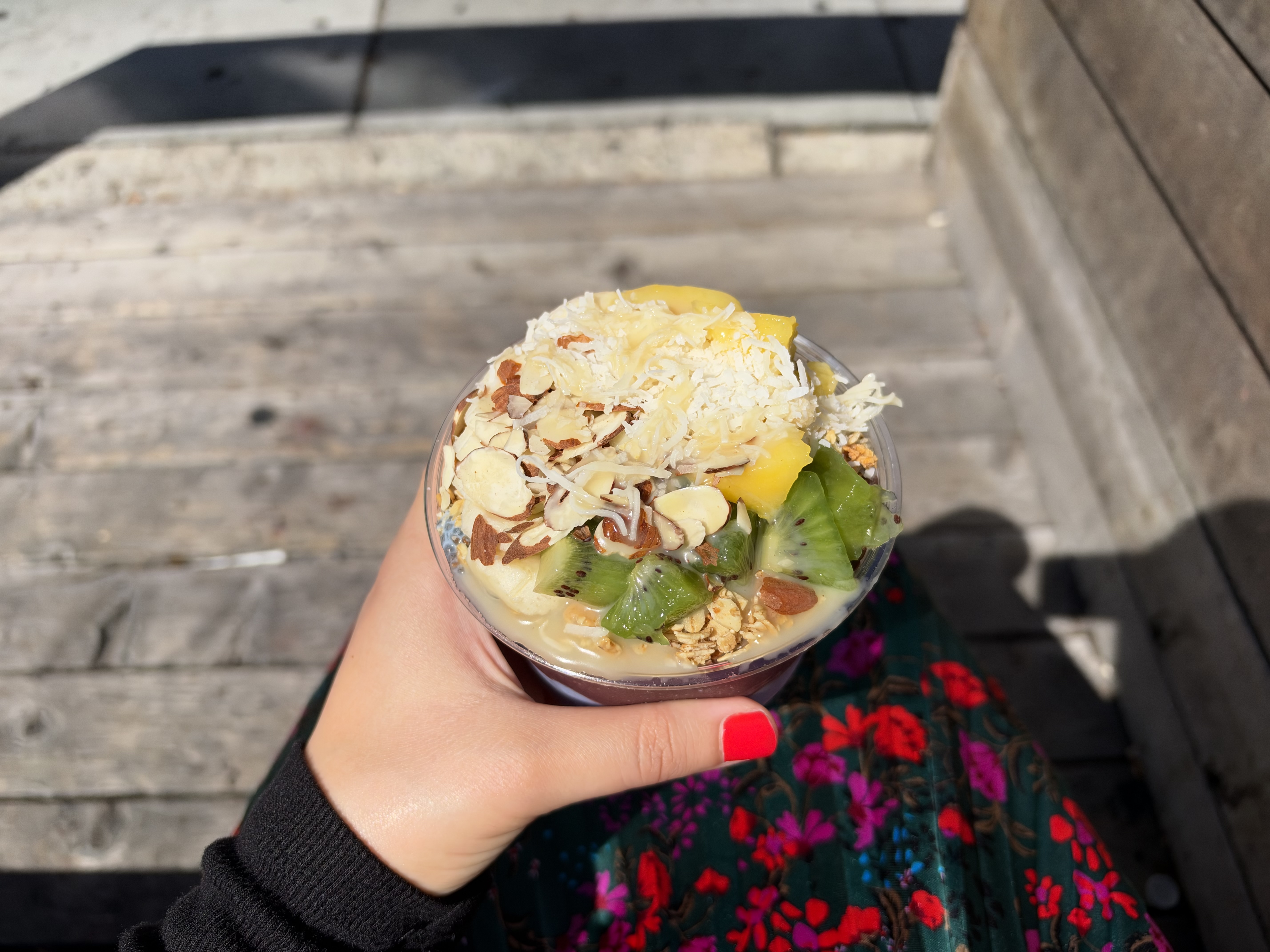An acai bowl with fruit on top, in someone's hand