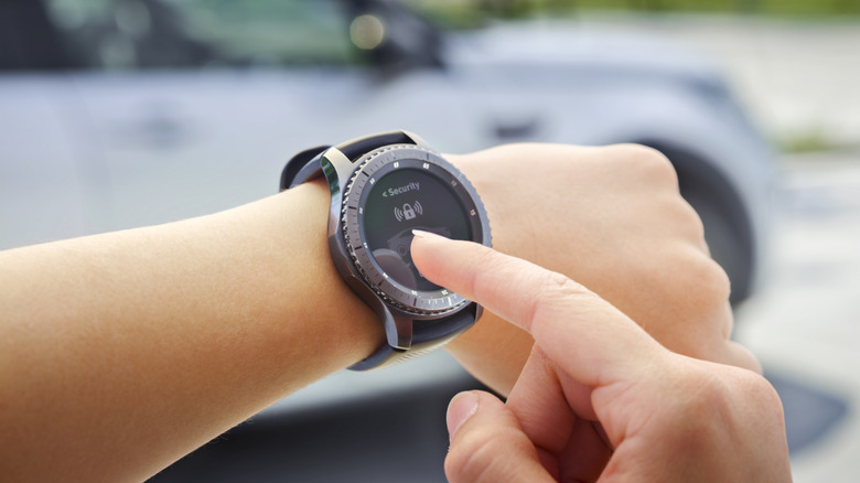 Close-Up of person touching screen of a Galaxy Watch, a blurred car can be seen in the backrground