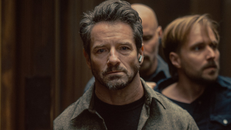Grady and guards transport Alex down a hallway in 