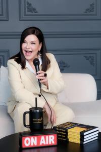 Karen Goslin, MSW, psychotherapist and best-selling author of Yellow Paint: Learning to Live Again, speaking into a microphone beside her books for her September 2026 Best Holistic Life Magazine feature on mental health and accountability.