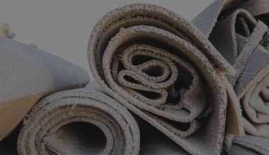 worn carpet being unrolled on a carpet recycling facility floor, more than 3