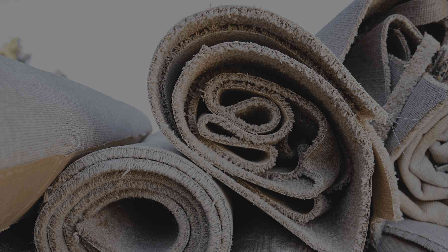 worn carpet being unrolled on a carpet recycling facility floor, more than 3
