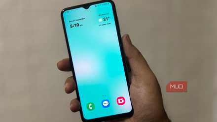 Person holding Samsung phone showing clean home screen with clock and weather