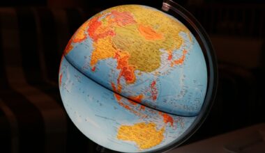 Blue and yellow physical globe showing Asia and Australia against a dark background
