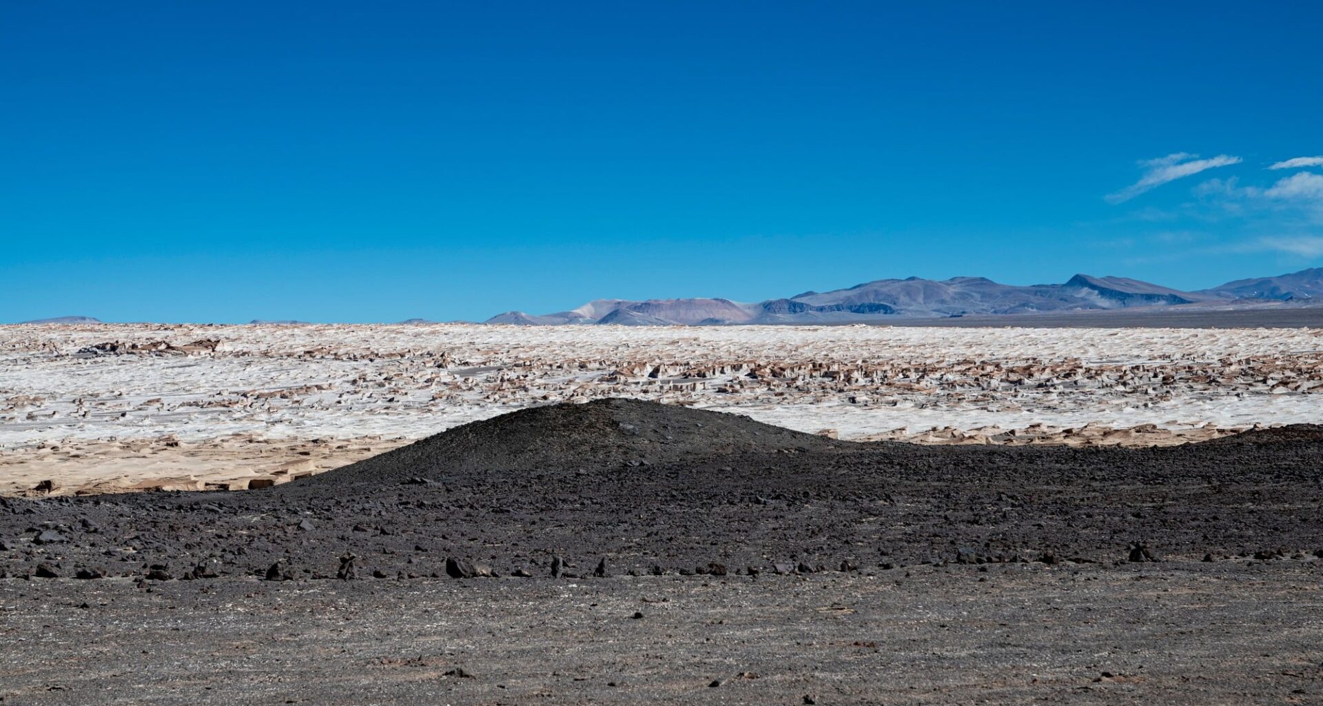 Dark volcanic terrain beside bright salt flats in Chile's Atacama Desert