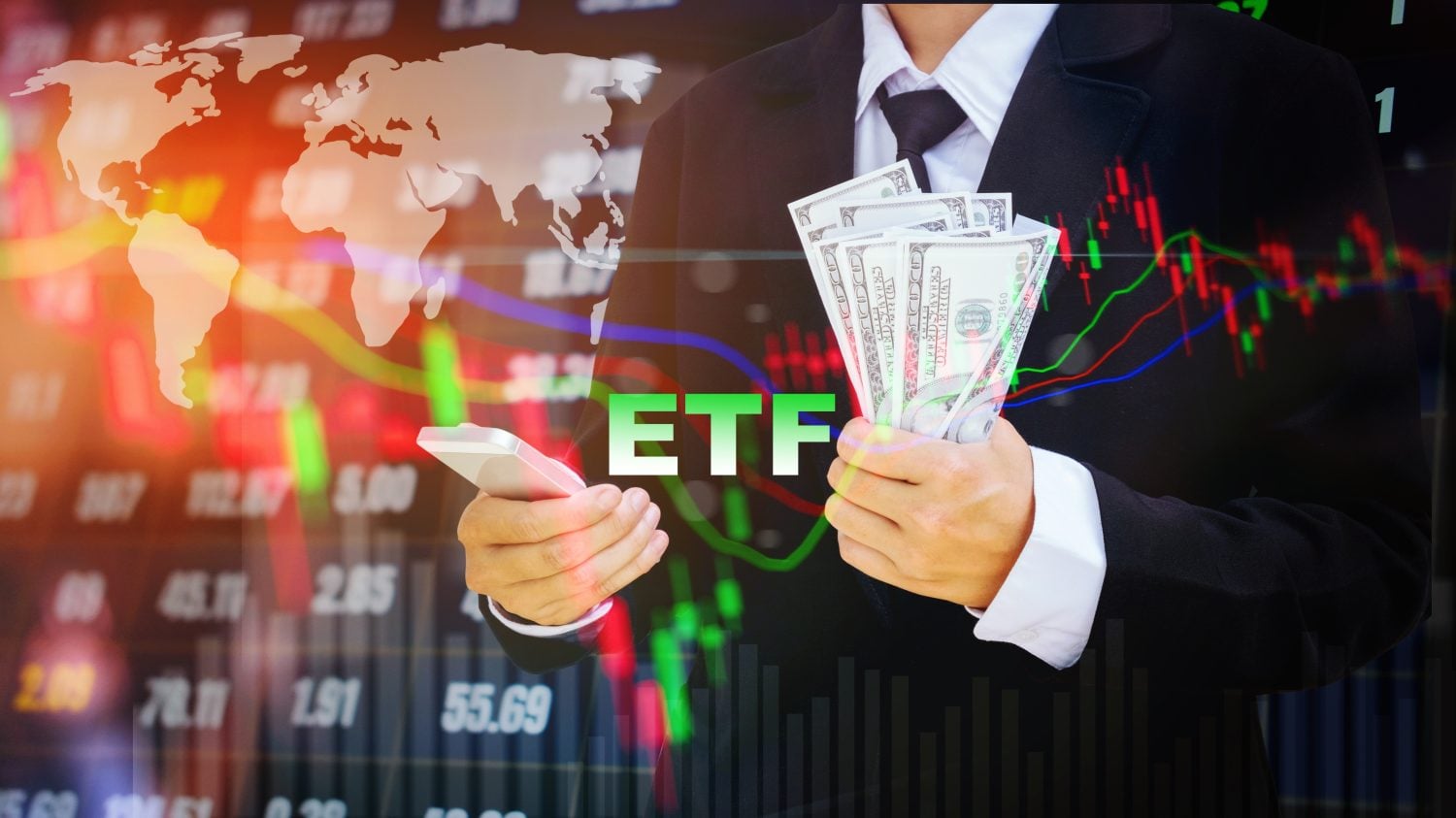 A person in a dark suit holds a silver smartphone in their left hand and a fan of one hundred U.S. dollar bills in their right hand. The green letters 'ETF' are visible in the center foreground. The background is a blurred, glowing digital display showing financial market data, including a world map, stock charts with red and green candlesticks, and various numerical figures, all overlaid with colorful trend lines.