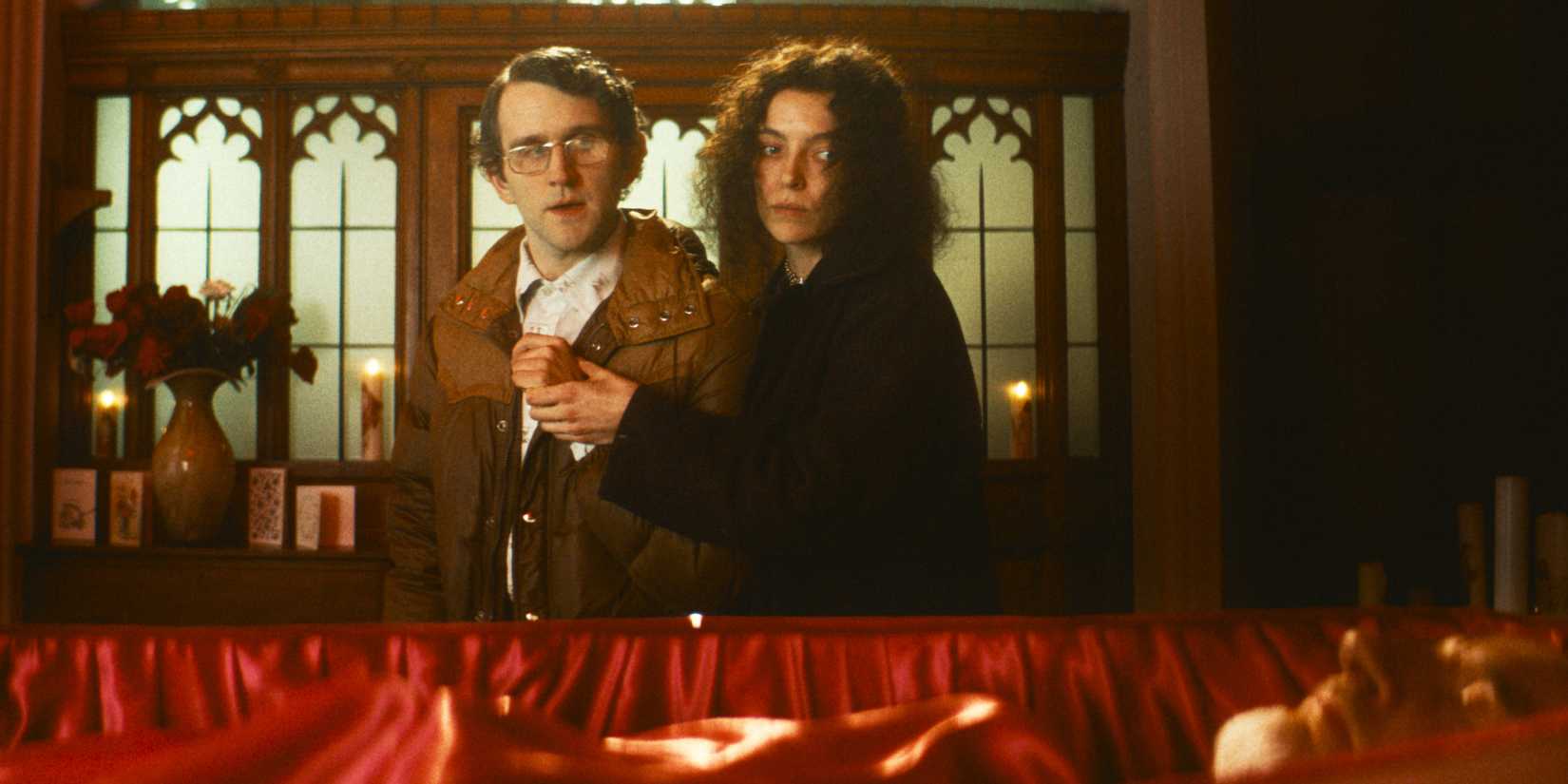 A man and woman stand at an open casket during a funeral.