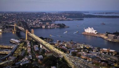 A view of Sydney Harbour in the evening seen from the sky, looking across the bridge and the Opera House.