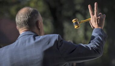 Back of a man holding a gavel in a suit.