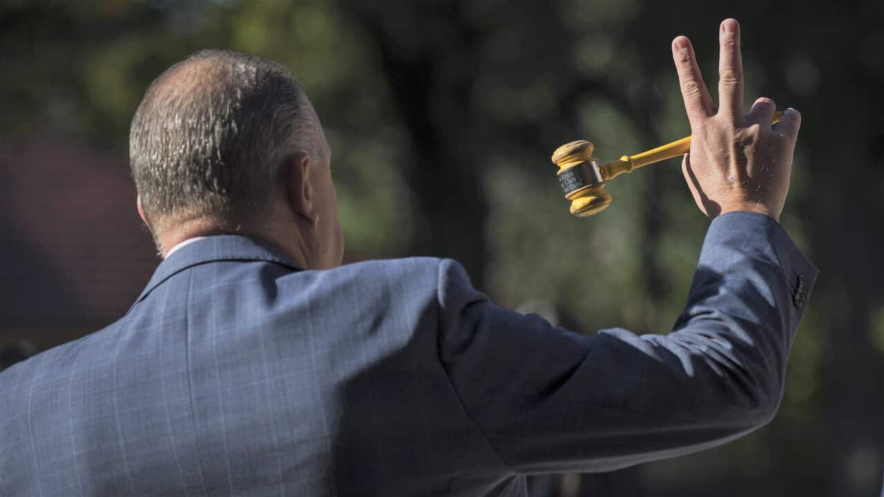 Back of a man holding a gavel in a suit.