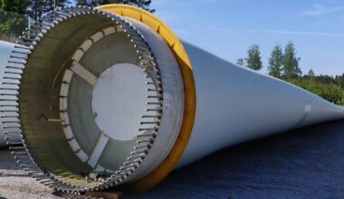 Large wind turbine blade lying on the ground with its composite structure exposed.