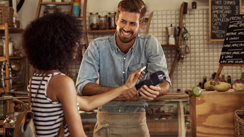 A woman making a contactless payment using their smartphone in a store.