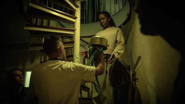 A TV Director and young actress filming a scene in a dark spiral staircase from the show Do Not Watch Alone