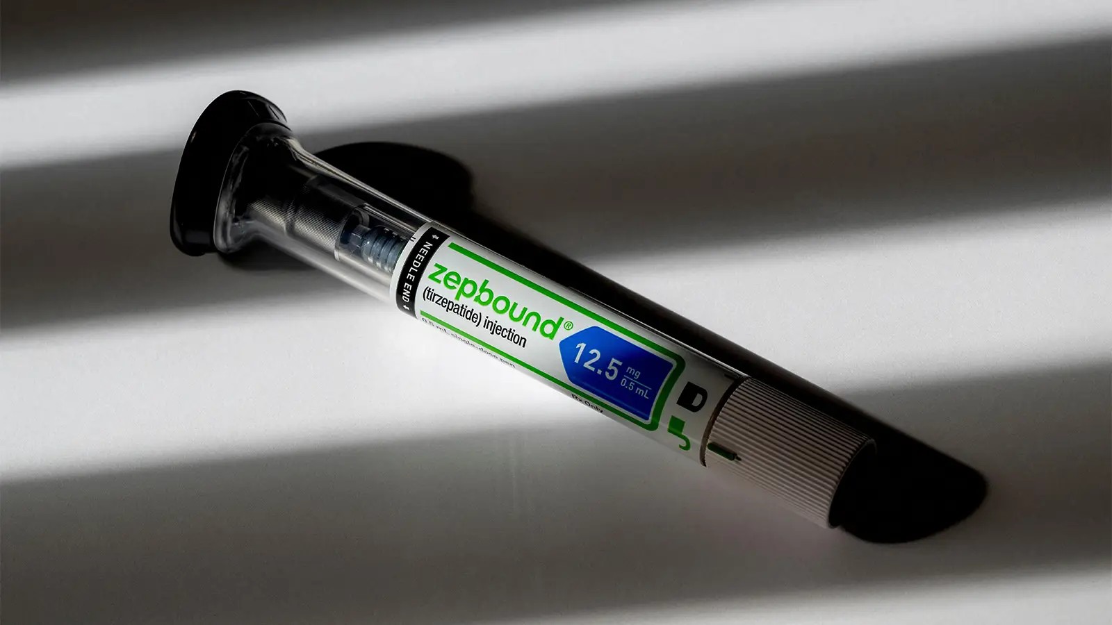 A photo of a Zepbound injection pen lying in shadows.