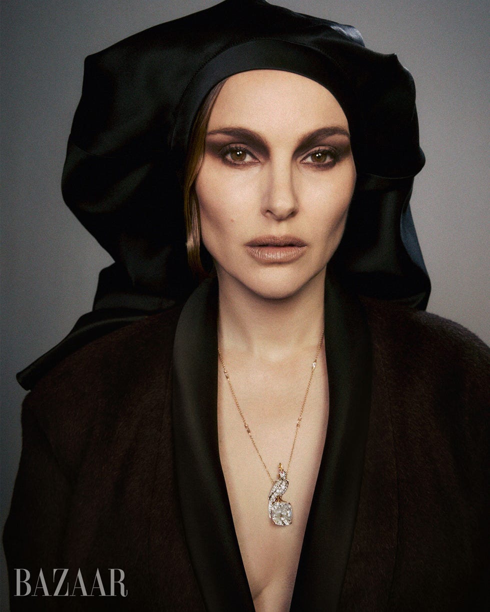 A woman in a black headscarf and robe, wearing a sparkling necklace, gazes directly at the camera. A woman in a black headscarf and robe, wearing a sparkling necklace, gazes directly at the camera.