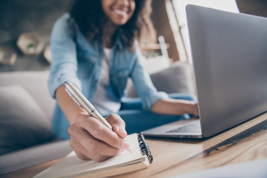 A dark-skinned woman with curly hair updated a to-do list at her desk