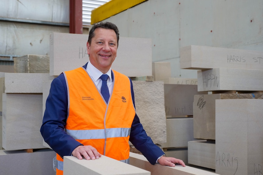 a man in a suit wearing an orange vest smiles